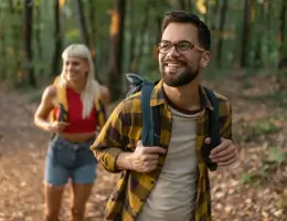 a man and a woman walking outside in a forest