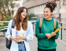 two women holding books and folders while walking outside